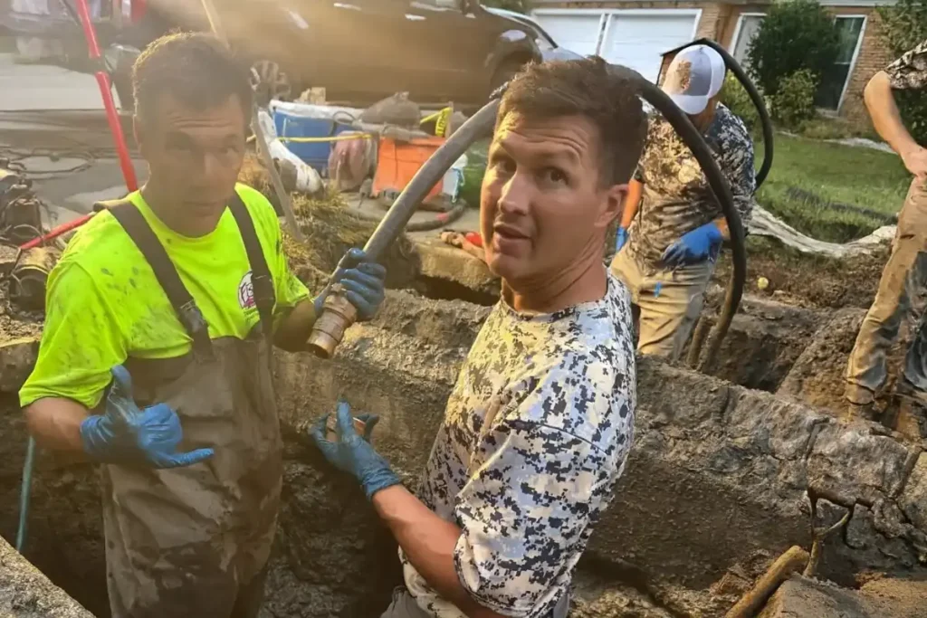 Technicians examining piping inside a muddy excavation to pinpoint the source of a drain leak during detection work in Evesham NJ.