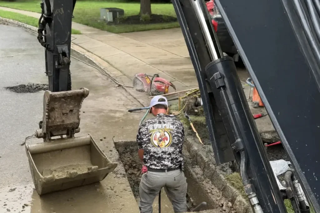 Sewer line repair replacement in New Jersey with an excavator opening the ground to access and replace a damaged underground sewer line.