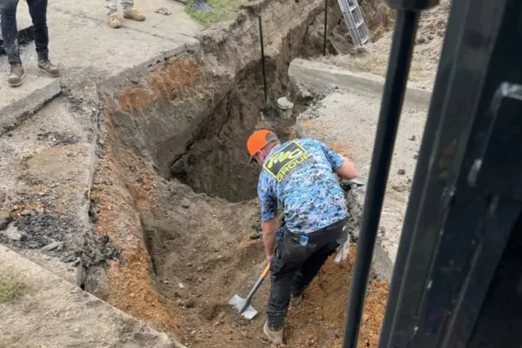 Sewer line repair in NJ with technicians excavating a deep trench to expose damaged underground sewer lines.
