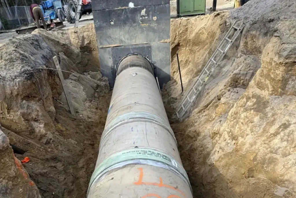 Large sewer line repair project in South New Jersey showing a deep excavation with a newly installed large-diameter sewer pipe connected to underground infrastructure.