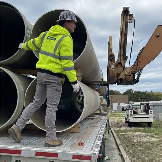 The Sewer Kings crew member loading concrete sewer pipes on a job site in South Jersey