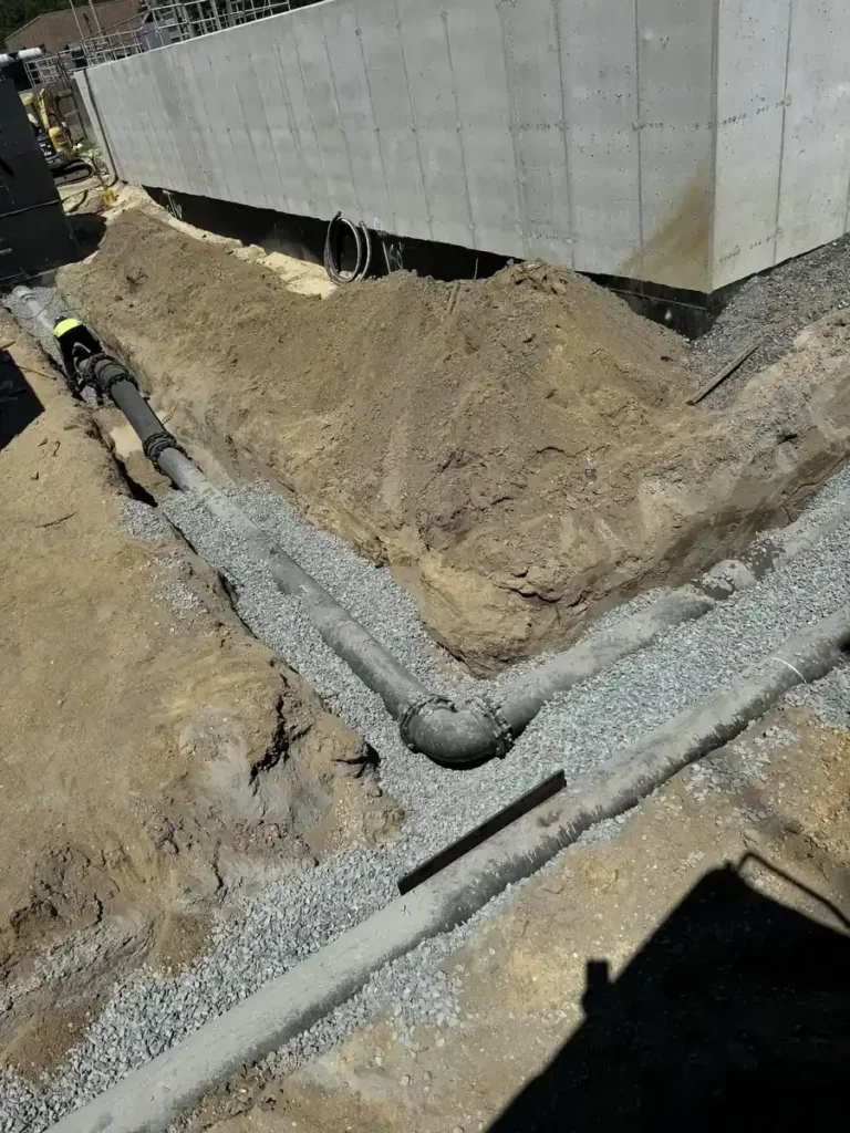 Drain pipe bedded in gravel beside a foundation, protected drain line work in Cherry Hill Township, NJ
