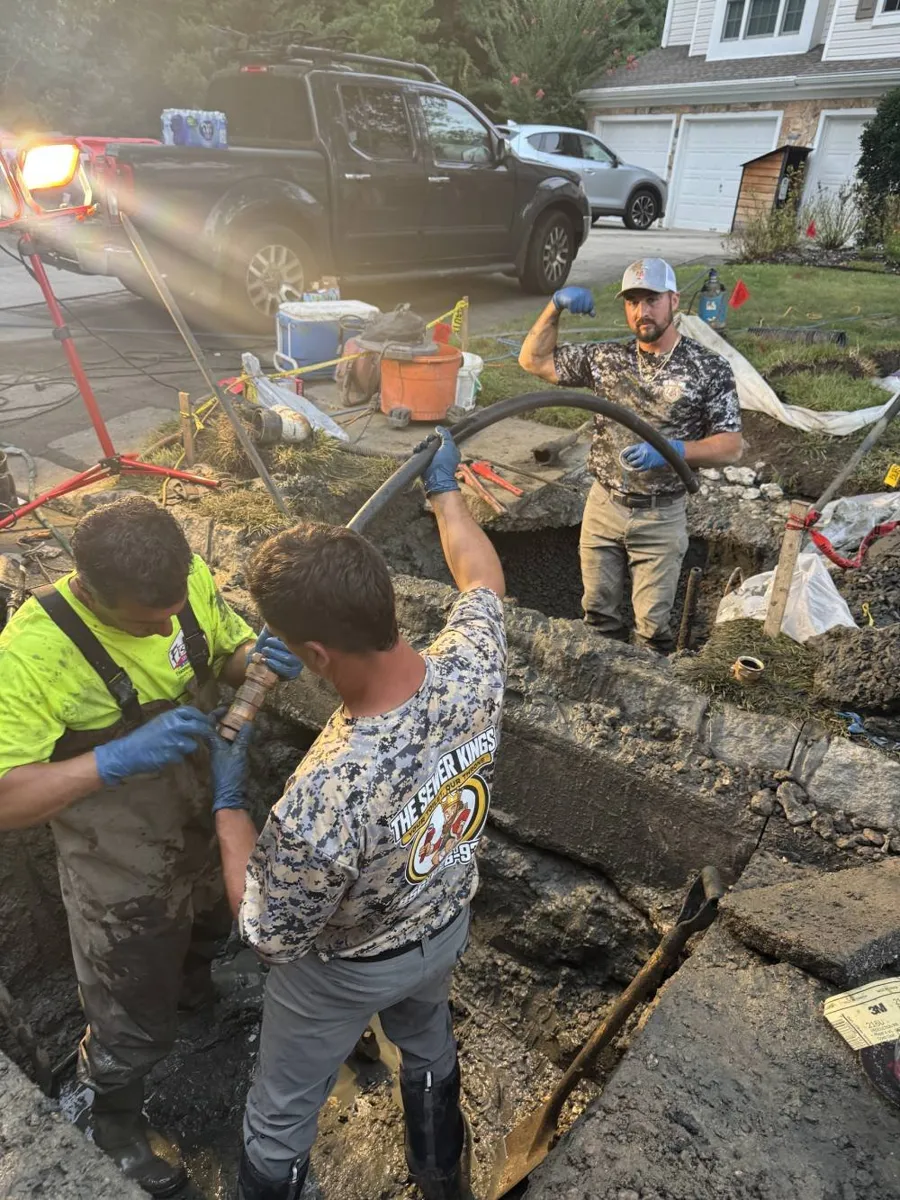 How Long Does Trenchless Pipe Bursting Take? Sewer Kings crew working in a lit pit at a home as evening falls
