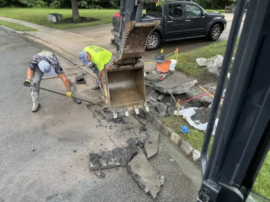 Crew and excavator opening the street to reach a blocked sewer line in Cherry Hill Township, NJ