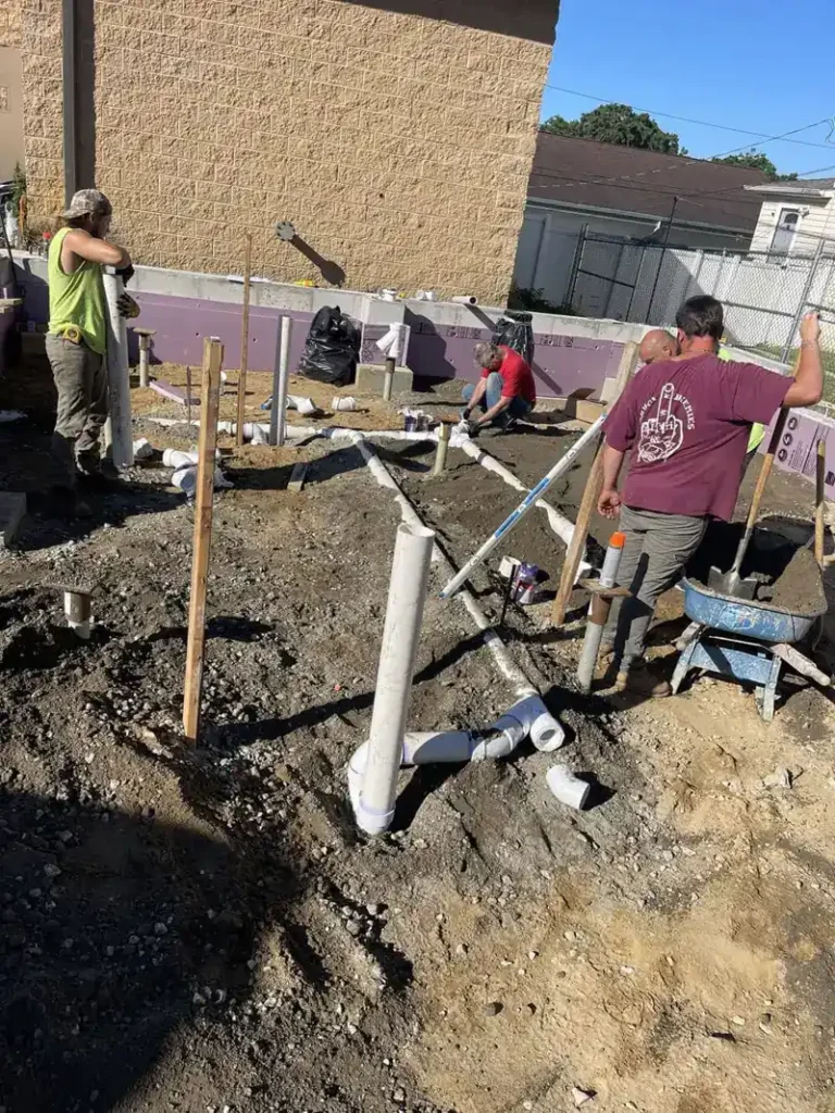 Why Outdoor Water Management Matters for Cherry Hill Township Yards Crew laying PVC lines in the ground beside a building, outdoor water management work in Cherry Hill