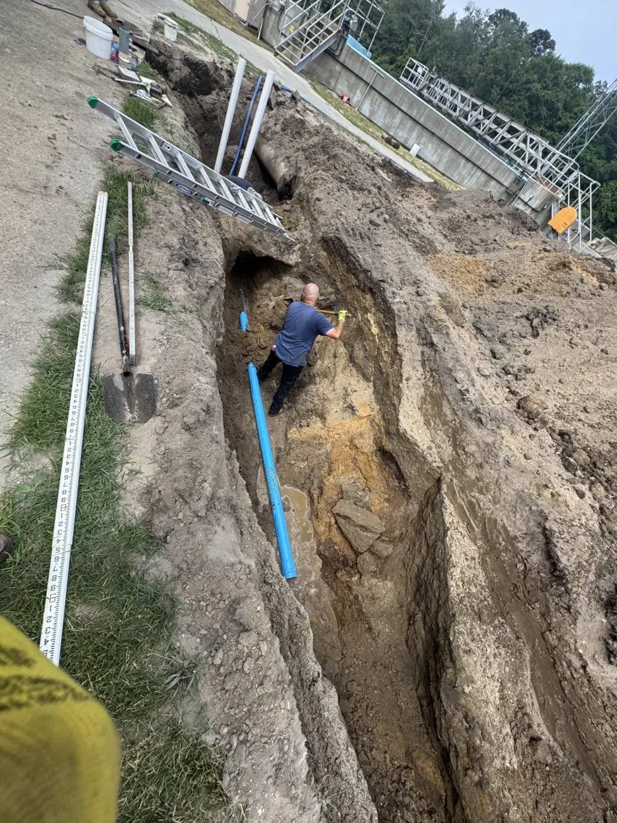 Can Trenchless Sewer Replacement Be Done in Winter? Deep narrow trench with a measuring rod and a worker next to a new pipe run