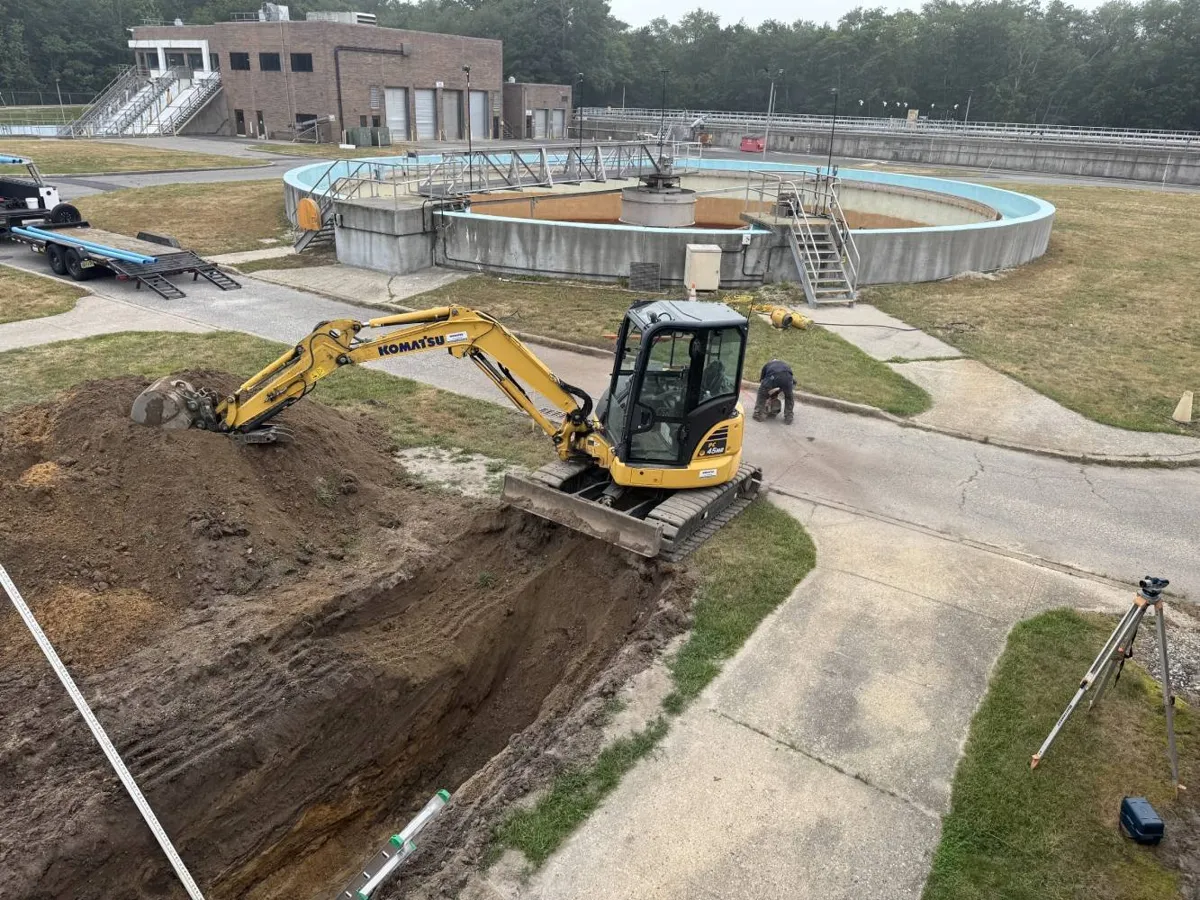 Trenchless Sewer Replacement vs. Traditional Dig-and-Replace Mini excavator digging a long trench along a concrete walkway