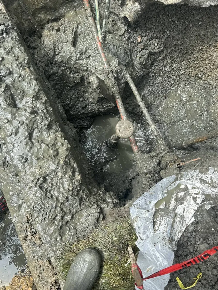 Signs Your Water Line Needs to Be Replaced Muddy dig site with water pooling around exposed pipes and fittings