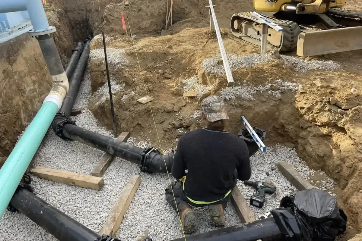 Commercial Technician fitting drain pipe on a gravel bed in an open dig in South Jersey