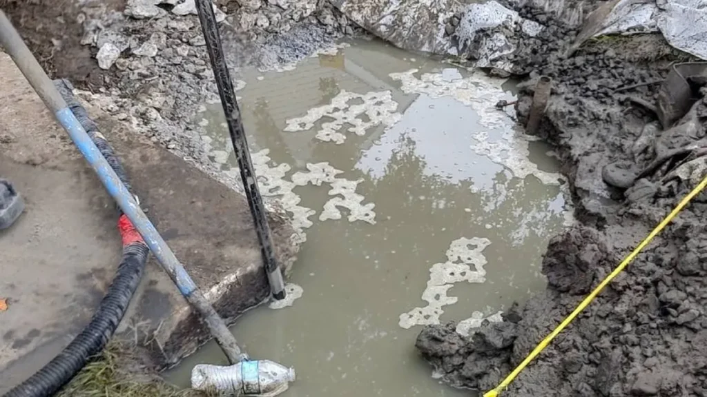 How Heavy Rain and Groundwater Get Into Cracked Sewer Lines in Evesham Flooded trench holding standing water at a curbside sewer line dig in Evesham, NJ