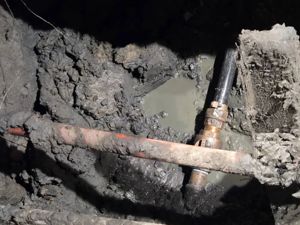 How Heavy Rain and Groundwater Get Into Cracked Sewer Lines in Evesham Old corroded sewer line and fittings exposed in a wet excavation in Evesham, NJ